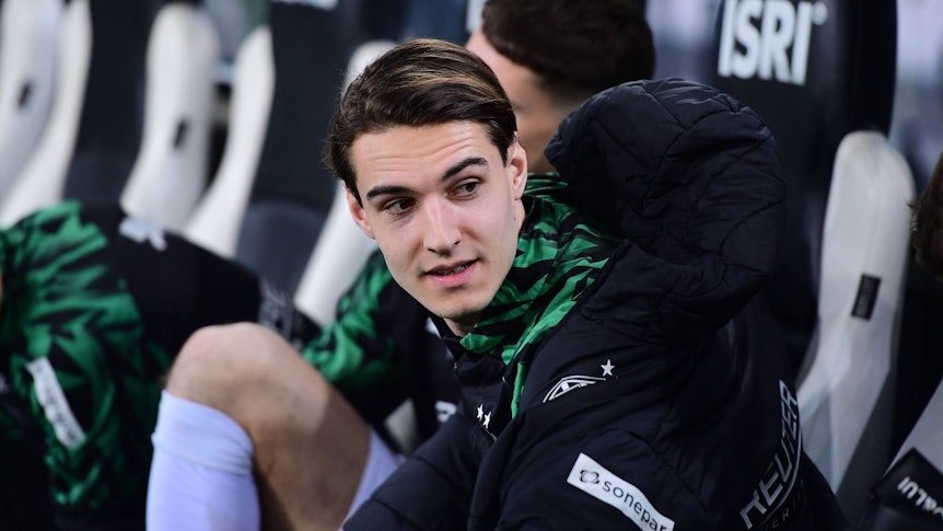 Borussia Mönchengladbachs Florian Neuhaus sitzt beim Bundesliga-Spiel gegen den VfL Bochum auf der Bank und spricht mit einem Teamkollegen.