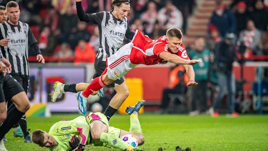 Kevin Behrens hebt ab, Moritz Nicolas kämpft am Boden um den Ball.