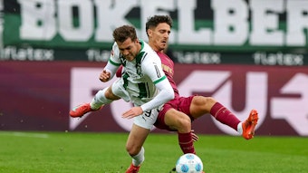 Borussia Mönchengladbachs Joe Scally und Augsburgs Dimitrios Giannoulis kämpfen um den Ball.