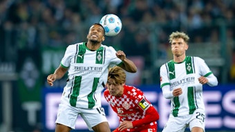 Borussia Mönchengladbachs Alassane Plea köpft den Ball, Mainz-Profi Kaishu Sano steht dahinter, Gladbachs Robin Hack beobachtet die Szene.