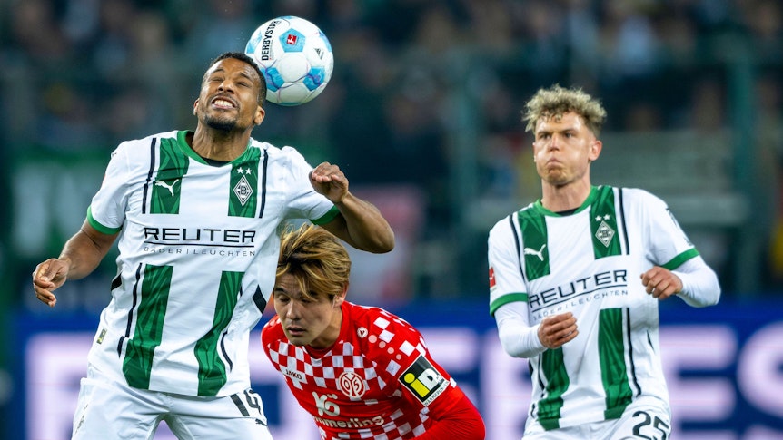 Borussia Mönchengladbachs Alassane Plea köpft den Ball, Mainz-Profi Kaishu Sano steht dahinter, Gladbachs Robin Hack beobachtet die Szene.
