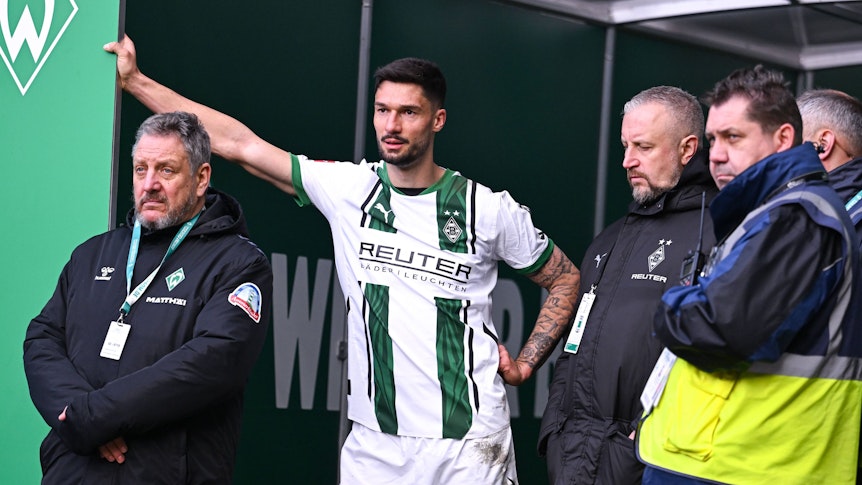 Borussia Mönchengladbachs Tim Kleindienst lehnt im Bremer Weserstadion mit einem Arm am Eingang zum Kabinentrakt und blickt auf das Spielfeld.