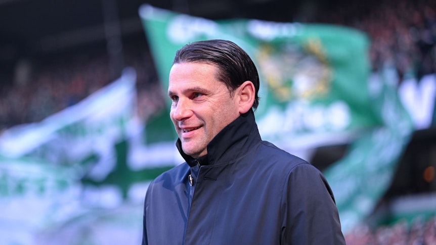 Gerardo Seoane lächelt vor der Kurve der Bremen-Fans.