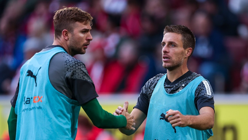 Die Gladbach-Reservisten Christoph Kramer und Patrick Herrmann klatschen sich während des Spiels beim 1. FC Köln auf dem Platz ab.