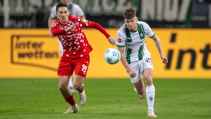 Borussia Mönchengladbachs Lukas Ullrich treibt den Ball, der Mainzer Anthony Caci verfolgt ihn.