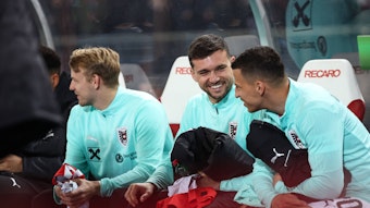 Stefan Lainer und Kevin Stöger sitzen auf der Bank und lachen miteinander.