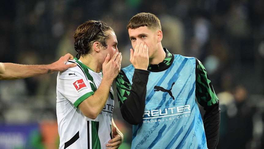 Die Gladbach-Profis Rocco Reitz und Philipp Sander unterhalten sich nach dem Bundesliga-Heimspiel gegen Werder Bremen mit vorgehaltener Hand vor dem Mund.