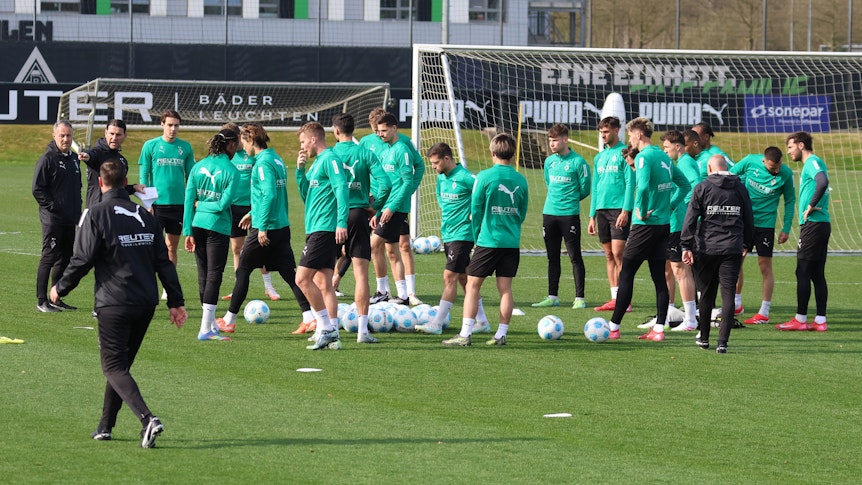 Die Gladbach-Profis und das Trainerteam auf dem Platz zum Training in der Sonne.