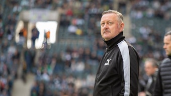 Roland Virkus schaut vor einem Bundesliga-Spiel konzentriert nach oben.