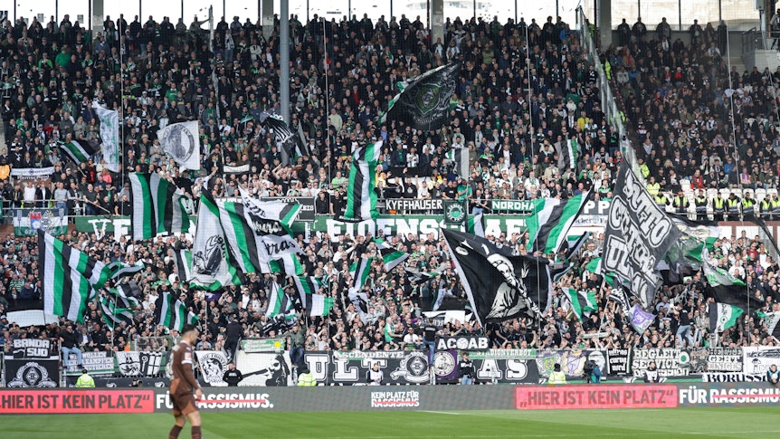 Gladbacher Auswärtsfans auf St. Pauli. Vorne steht auf einer Bande „Hier ist kein Platz für Rassismus.“