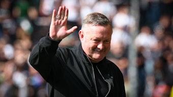 Roland Virkus grüßt bei einem Spiel von Borussia Mönchengladbach.