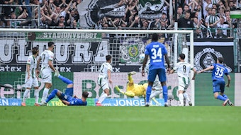 Der Strafraum von Borussia Mönchengladbach. Die Spieler schauen auf den Ball, der im Tor einschlägt.