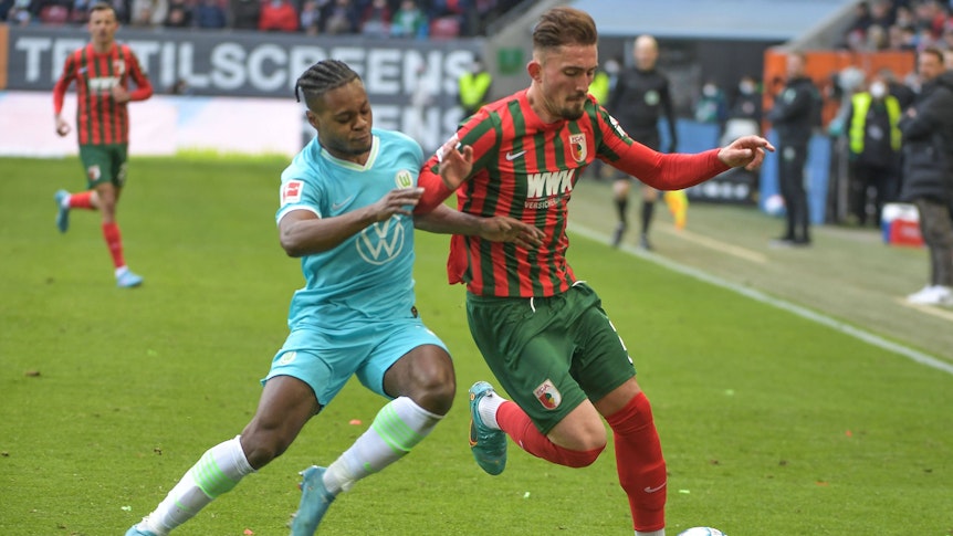 Ridle Baku und Andi Zeqiri beim Bundesliga-Duell zwischen Wolfsburg und Augsburg am 4. März 2022 im Zweikampf.