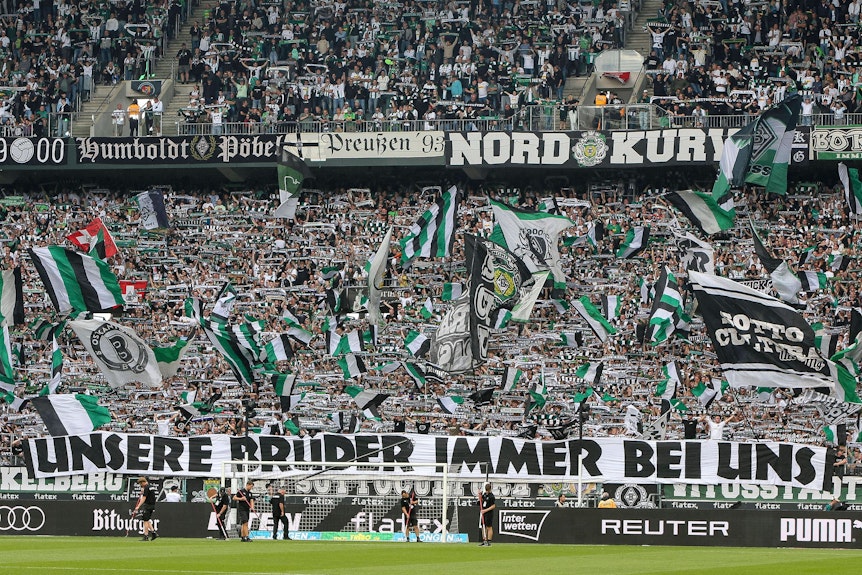 Fans von Borussia Mönchengladbach mit einem Banner und einem Meer aus Fahnen.