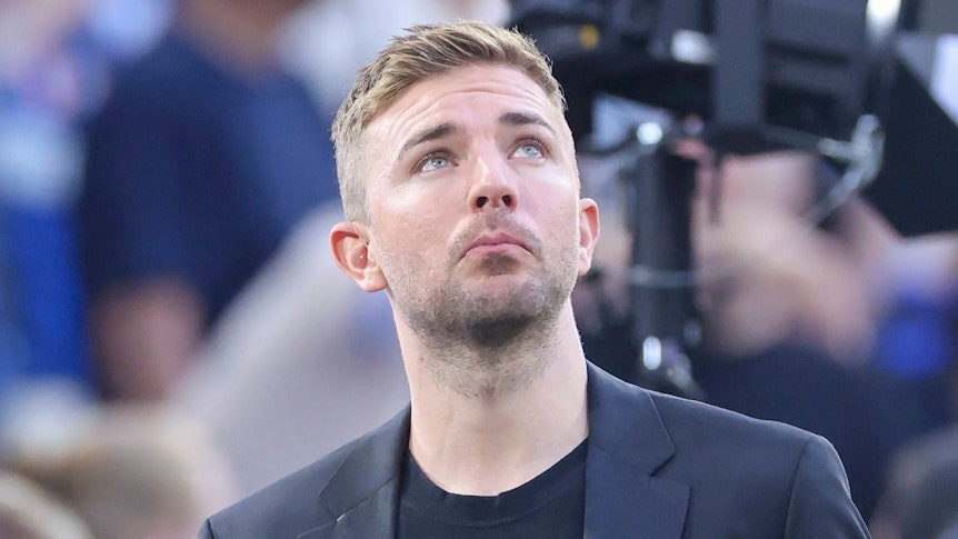 Christoph Kramer schaut im Anzug in den Abendhimmel.