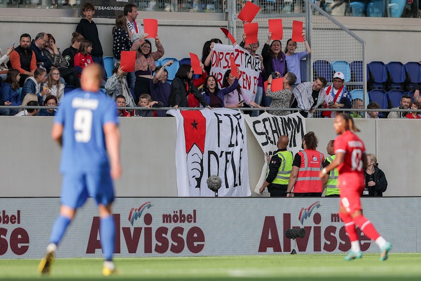 Fans protestieren mit Bannern, auf denen steht „Rote Karte für die FLF“ und „Schäm dich, FLF“.