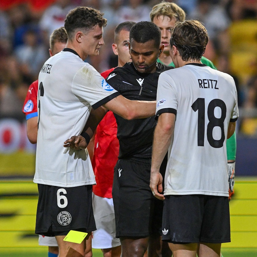 Dem Schiedsrichter, der zwischen Eric Martel und Rocco Reitz steht, fällt die Gelbe Karte aus der Hand.