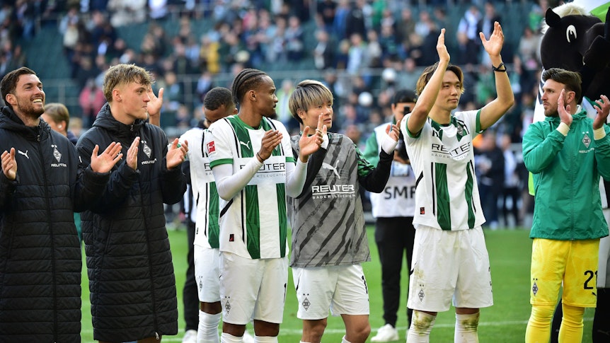 Spieler von Borussia Mönchengladbach feiern mit den Fans vor der Nordkurve.