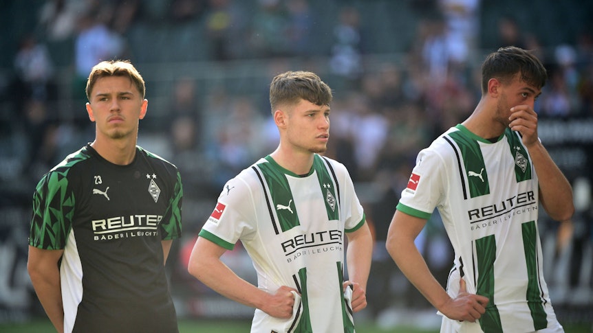 Noah Pesch steht neben Lukas Ullrich und Fabio Chiarodia vor der Fankurve.