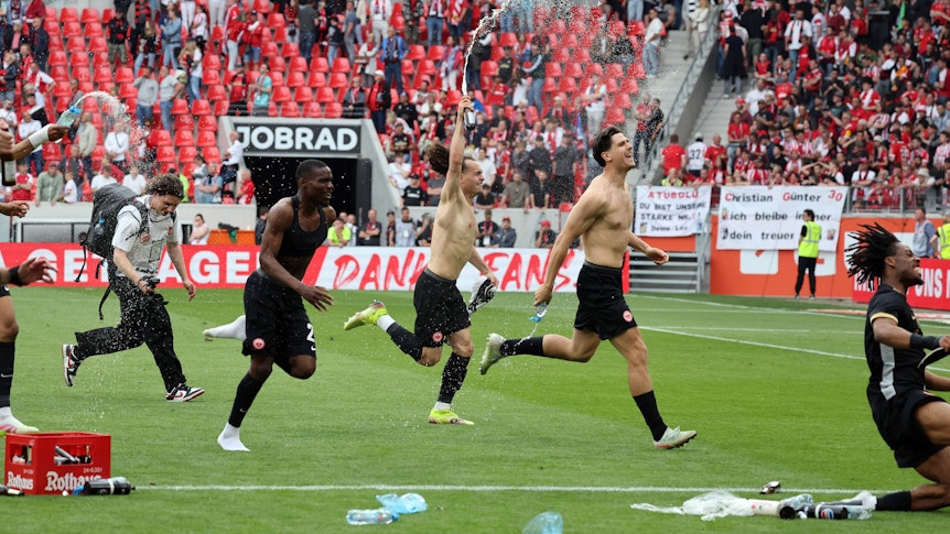 Frankfurt-Spieler jubeln oberkörperfrei vor dem Gästeblock in Freiburg.