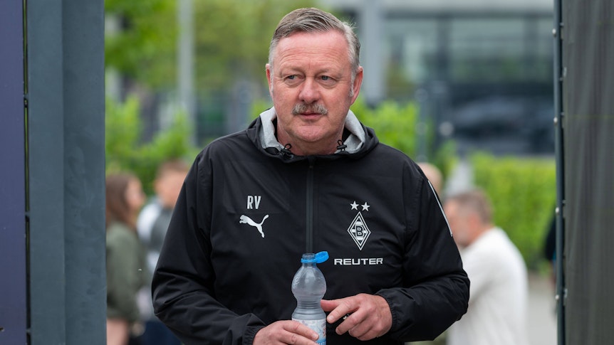 Roland Virkus betritt mit einer Wasserflasche den Trainingsplatz.