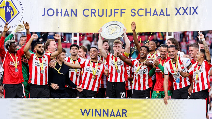 Die Spieler von PSV Eindhoven jubeln mit einer Schale auf einer Tribüne.
