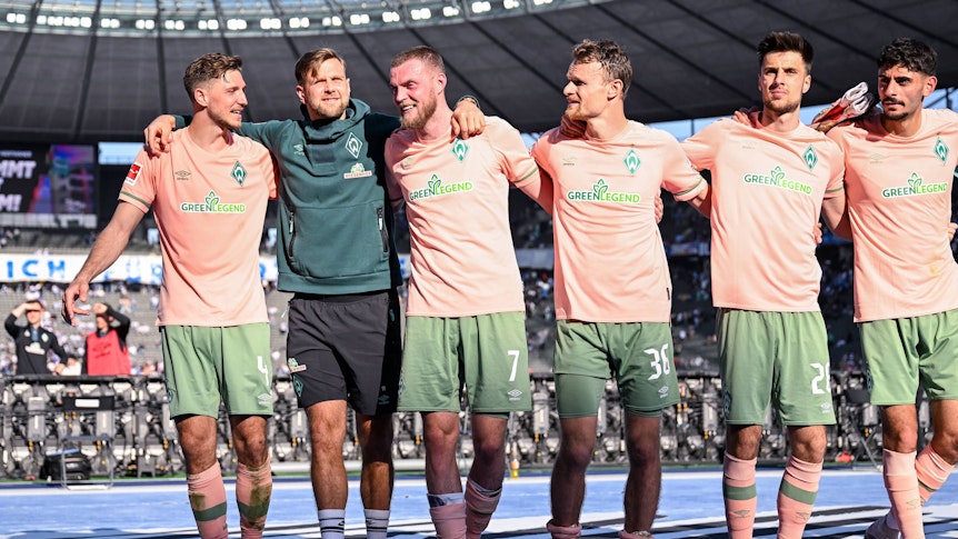 Spieler von Werder Bremen jubeln mit den Fans im Olypiastadion.