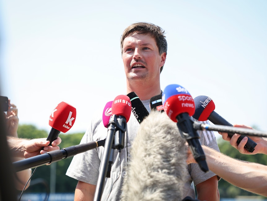 HSV-Trainer Merlin Polzin spricht vor Mikrofonen.