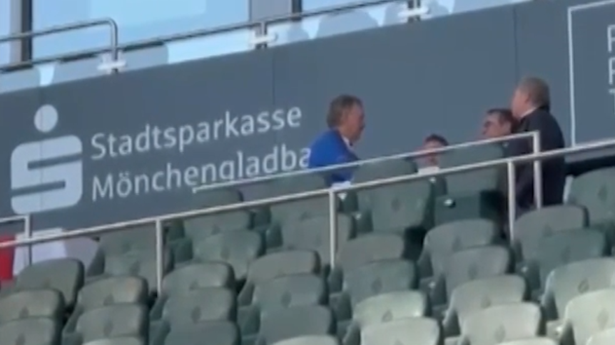 Peter Neururer und mehrere andere Personen sitzen auf der Tribüne im Borussia-Park.