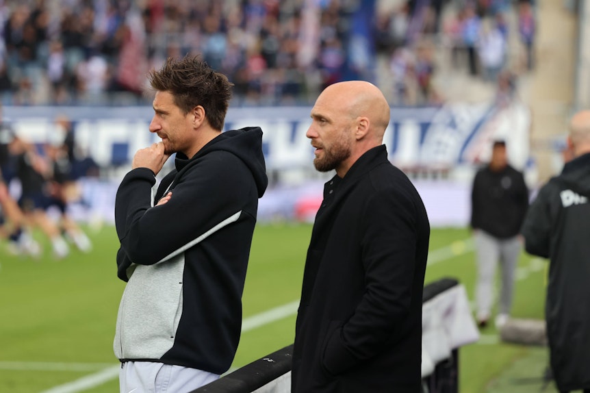 Vincent Wagner und Sportboss Niks-Ole Book beobachten das Aufwärmen.