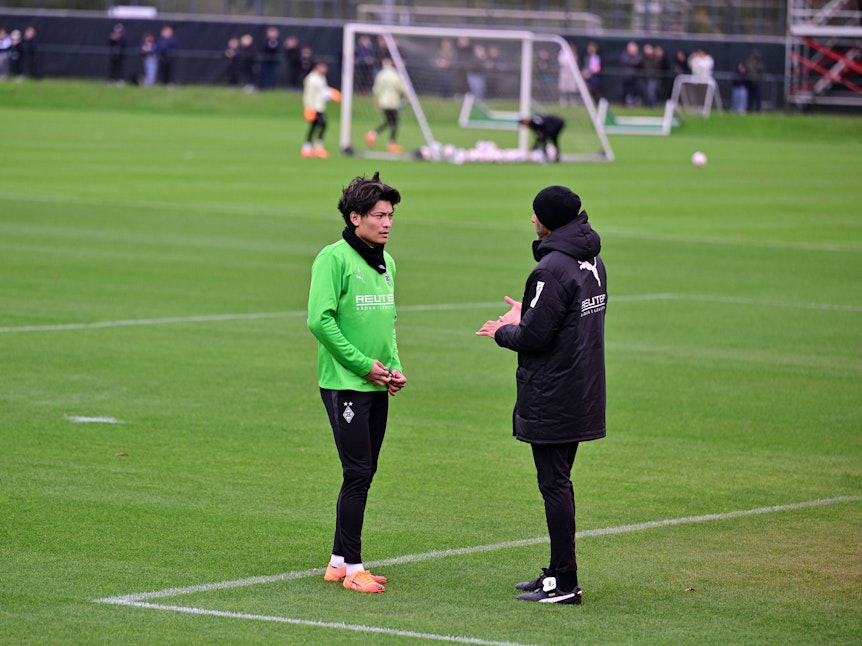 Shuto Machino spricht mit einem Trainer von Gladbach.